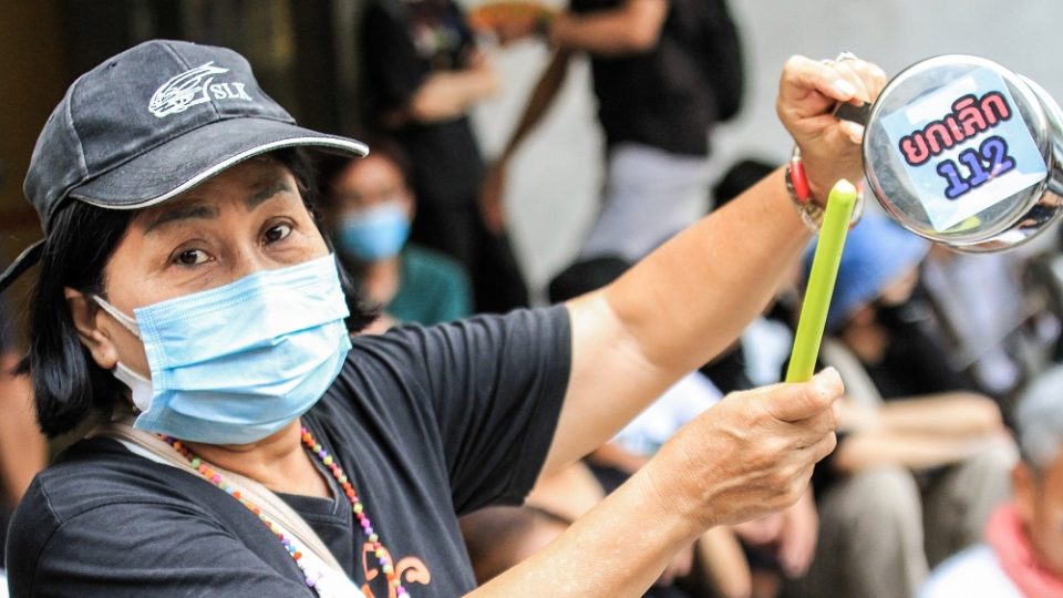 A protester on Feb. 10 at the Pathumwan Skywalk bangs pots and pans to call for abolition of lese majeste law. Photo: Coconuts Bangkok
