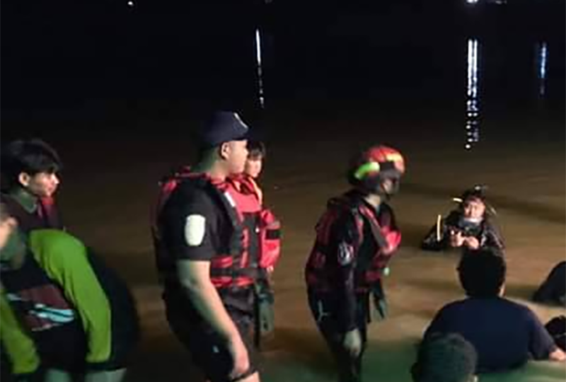 Rescue personnel search a pond in Kalasin province Tuesday night for the body of a missing 15-year-old boy.
