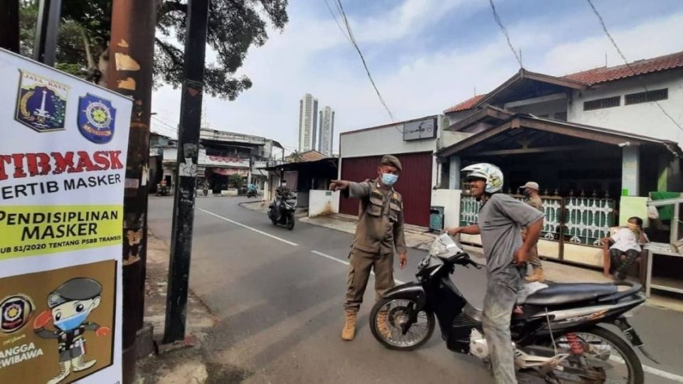 An officer from the Public Order Agency (Satpol PP) reminding a motorist to put on his face mask in West Jakarta. Photo: Twitter/@SatpolPP_DKI