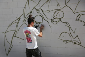 Australian mural artist Damien Mitchell is outlining the design on the wall. Photo: Thirdblade Photography