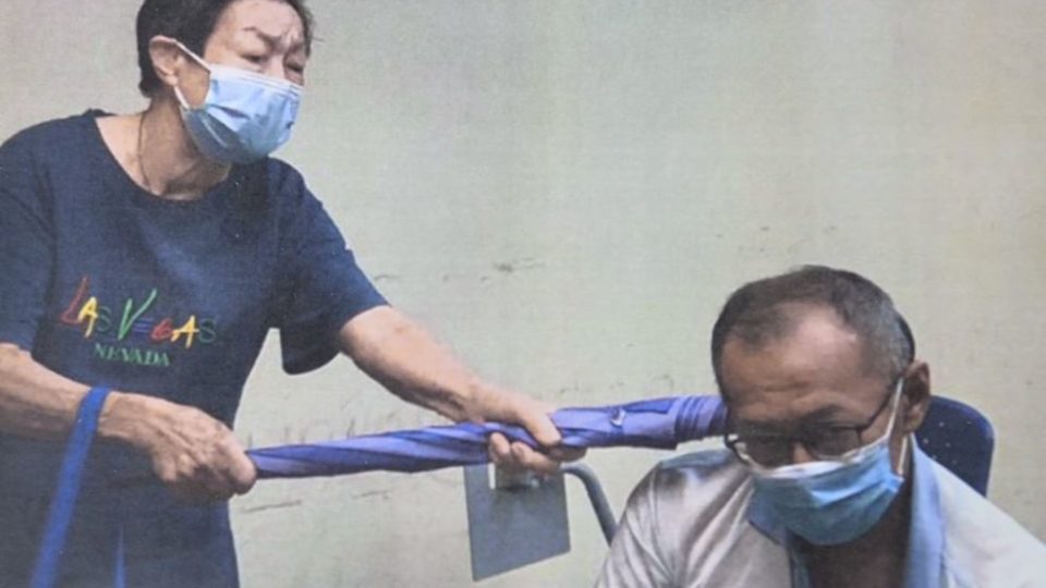 Kong Sew Koi beats her son with an umbrella. Photo: MCA
