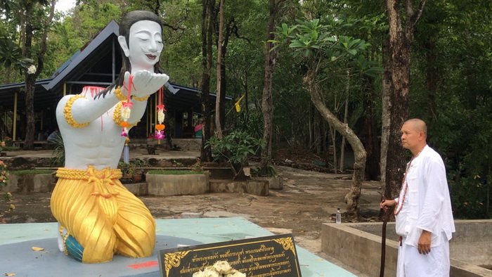 A disciple of temple abbot Dhammakorn Wangphrecha at the site where the latter killed himself using a homemade guillotine last week by a headless statue of the deity Indra.