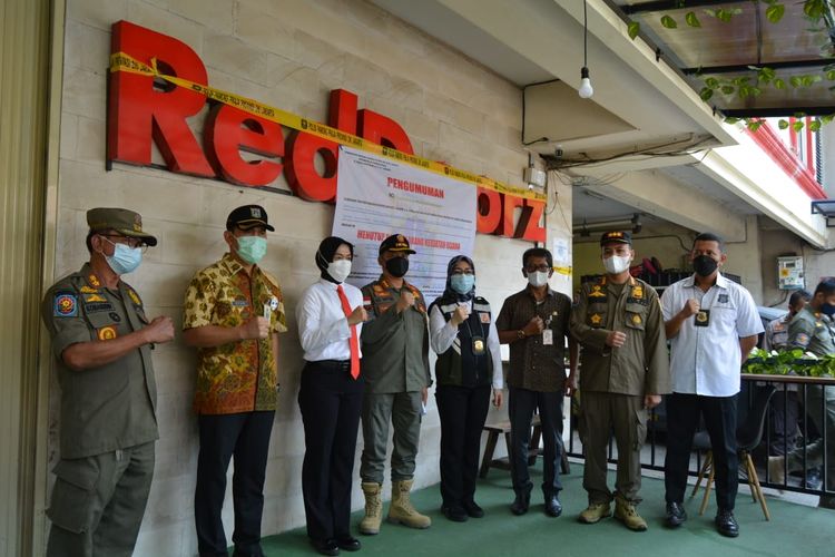 Officials posing in front of the shuttered RedDoorz budget hotel in Tebet, South Jakarta. Photo: Satpol PP