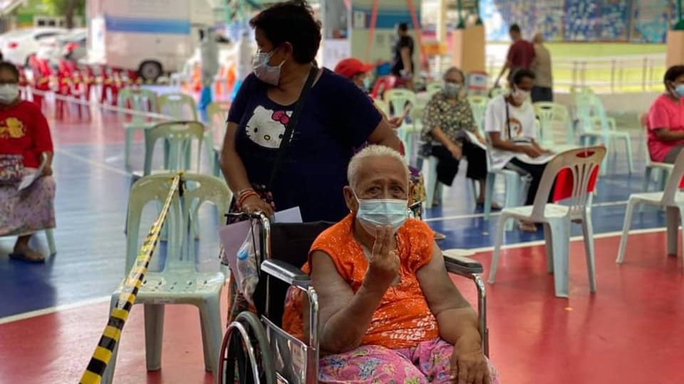 A Khlong Toei resident raises two fingers at a vaccination site. Photo: Khlong Toei District Office
