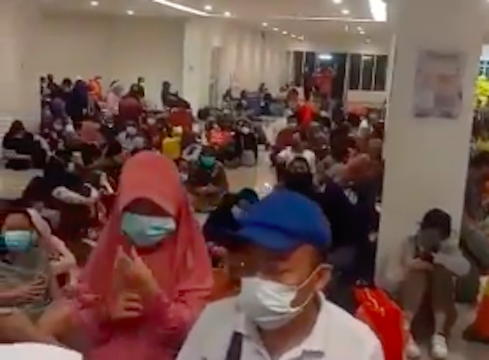 Patients sitting on the floor as they wait to be admitted to the Wisma Atlet COVID-19 quarantine facility in Jakarta. Photo: Video screengrab from Twitter/@dr_tompi
