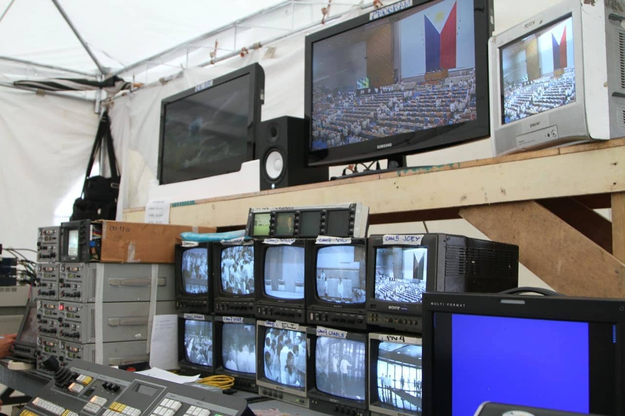 'Nag-aabala akong mag-Filipiniana pero yung totoo, yung pwesto namin ay sa tent sa labas ng Batasan. 😂Shared tent ito with RTVM. Dito dinidirect yung buong show. Nung 2013, aside from clicking the slides, inassign din nila akong taga-announce ng pan ng camera. So nakikinig ka kay Sir pero nakikinig ka rin sa instructions ng director sa headset. Filed under: #NeverAgain' 