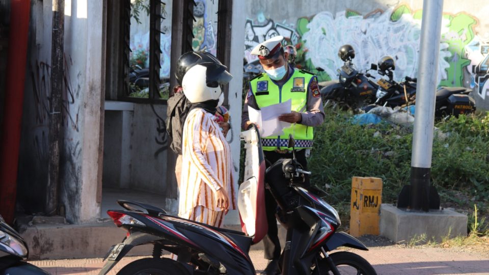 A police officer checking papers required to travel between regions in Bali during Emergency PPKM. Photo: Buleleng Police