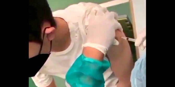 Video screengrab showing a Jakarta vaccinator injecting a teenage boy with an empty syringe.