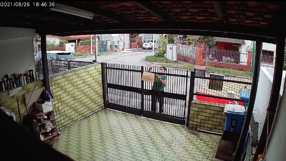 Woman just helps herself to a delivery parcel left hanging Thursday evening on a Macpherson Garden Estate gate. Image: David Loh/Facebook
