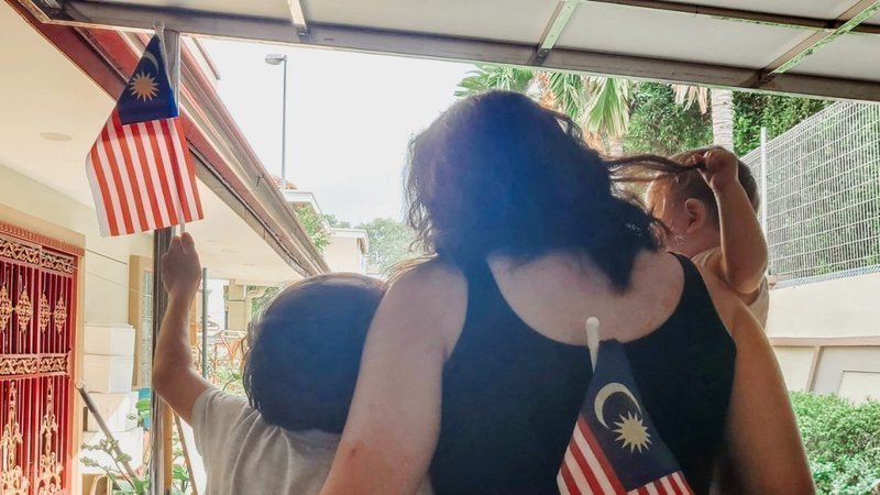 A mother with her two children waving Malaysian flags. Photo: Family Frontiers/ Change.org
