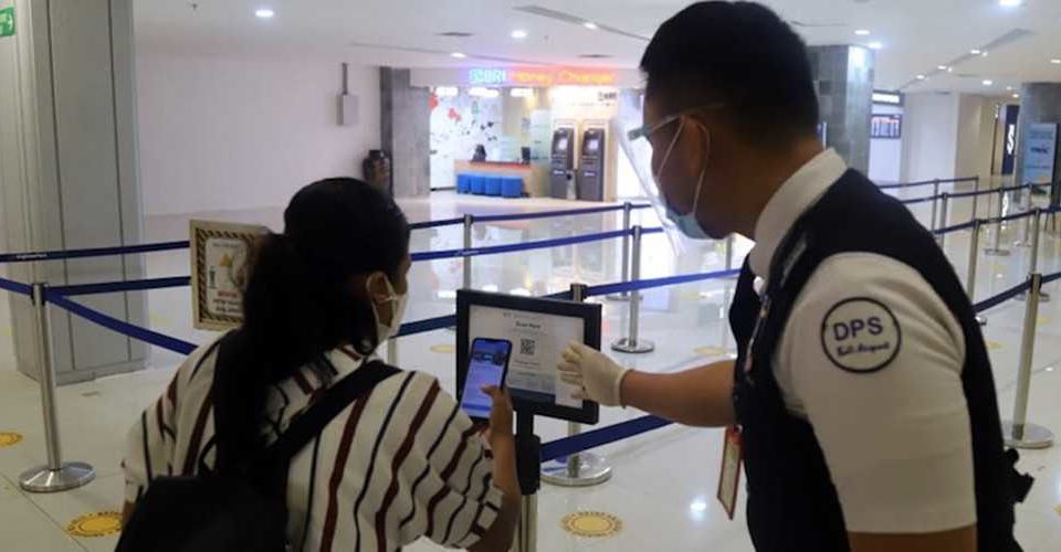 An airport officer showing a passenger how to use the PeduliLindungi app. Photo: Angkasa Pura I