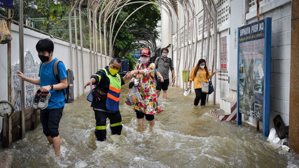 People wade through floodwaters at the Siphraya Pier in Bangkok. Photo: Bang Rak District Office / Facebook