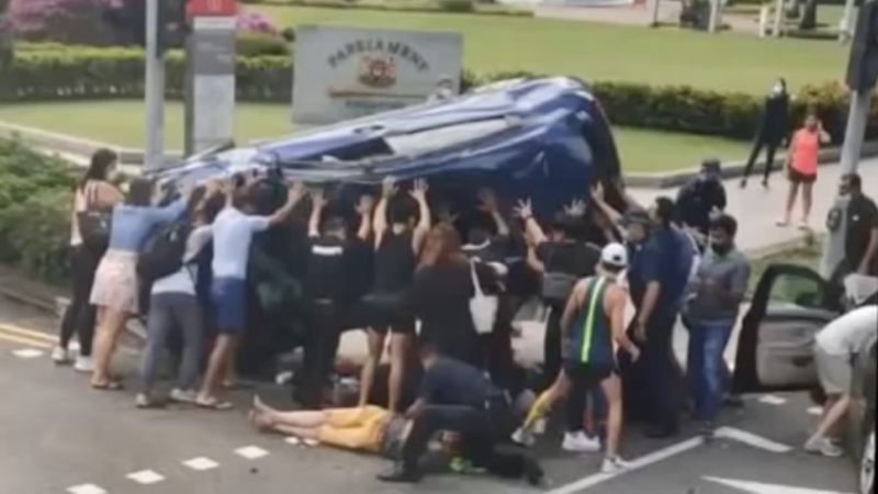 About a dozen people help flip a blue Honda at an accident near the Parliament House yesterday morning. Photo: Whatsapp
