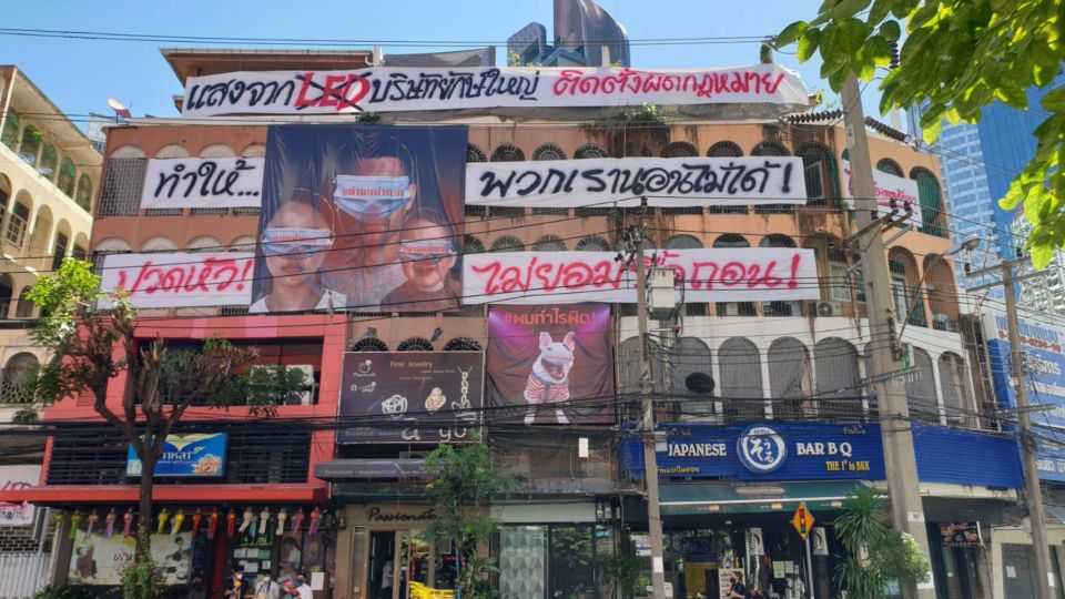 A visit on Tuesday found that a block of buildings in Thonglor covered with banners protesting the blazing billboard. Photo: Coconuts Bangkok