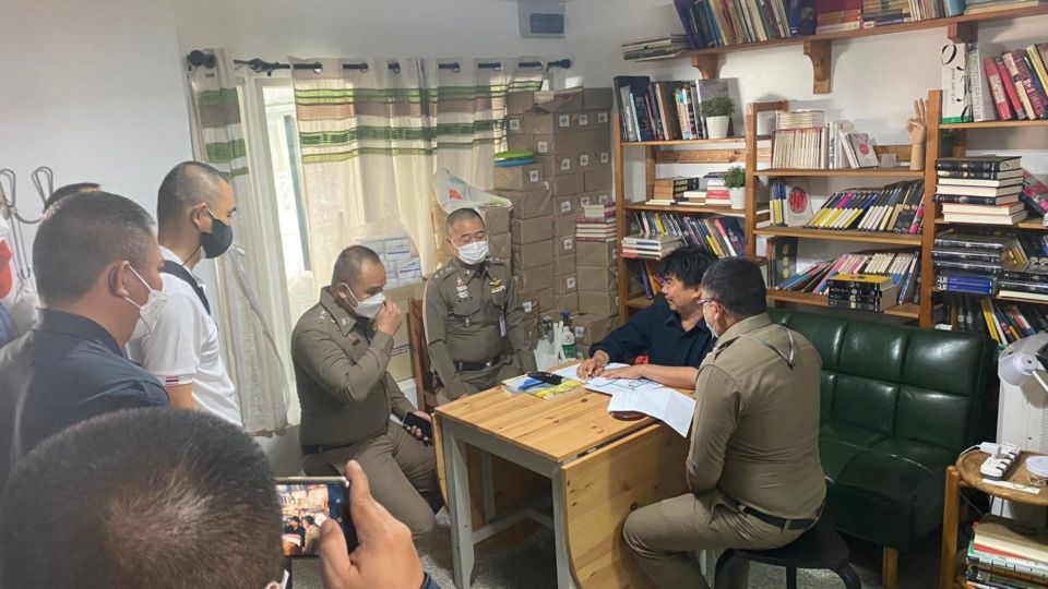 Fa Diew Kan editor Thanapol Eawsakul, seated in a blue shirt, talks Thursday morning to the police raiding his office. Photo: Fa Diew Kan 