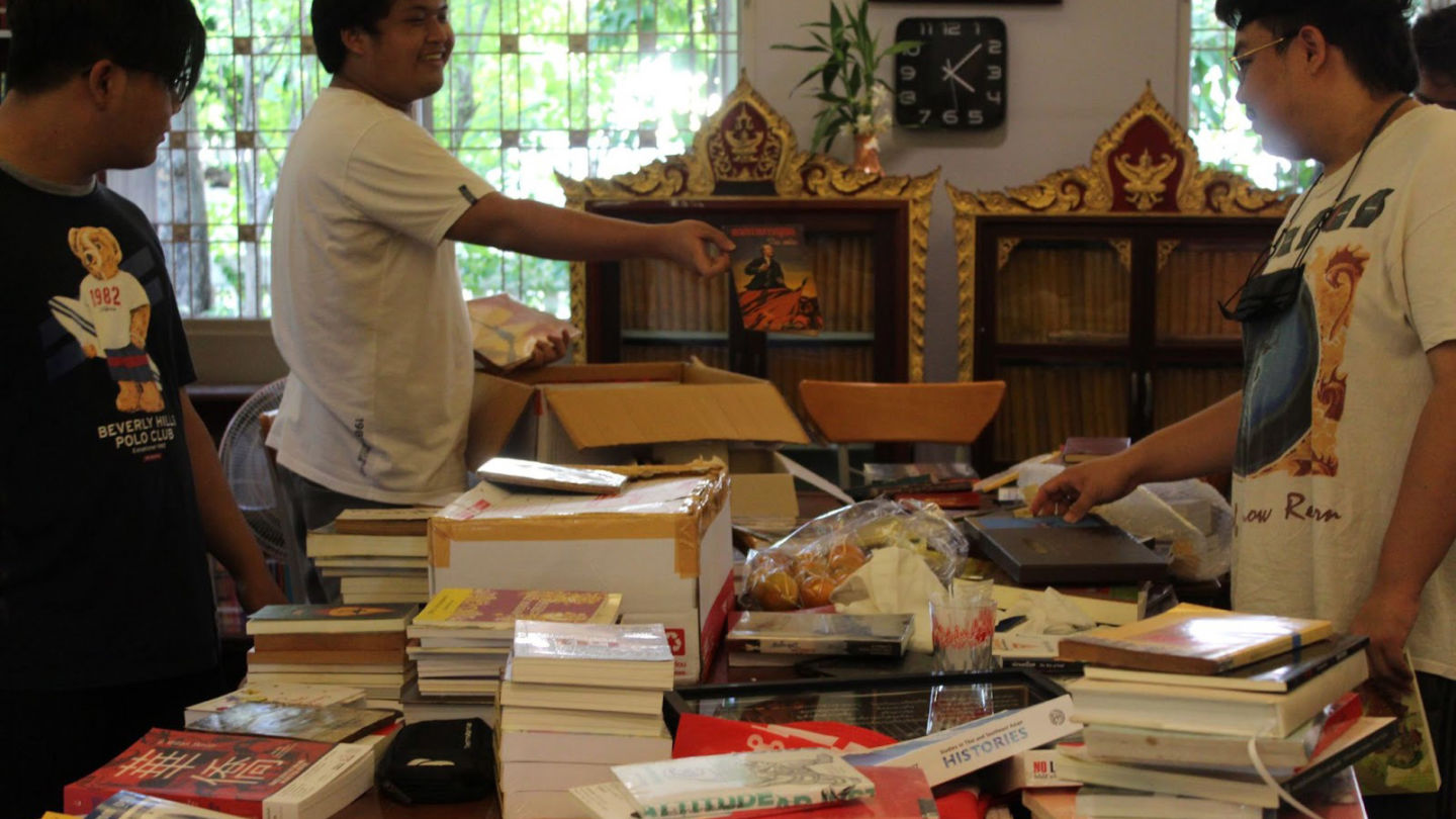 Founders of the 1932 People’s Space Library stand over a table of books waiting to be shelved. Photo: Tara Abhasakun