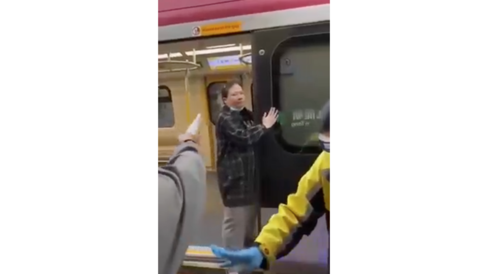 Screengrab of a video on internet of a woman spitting and smearing saliva on the door of an MTR train.