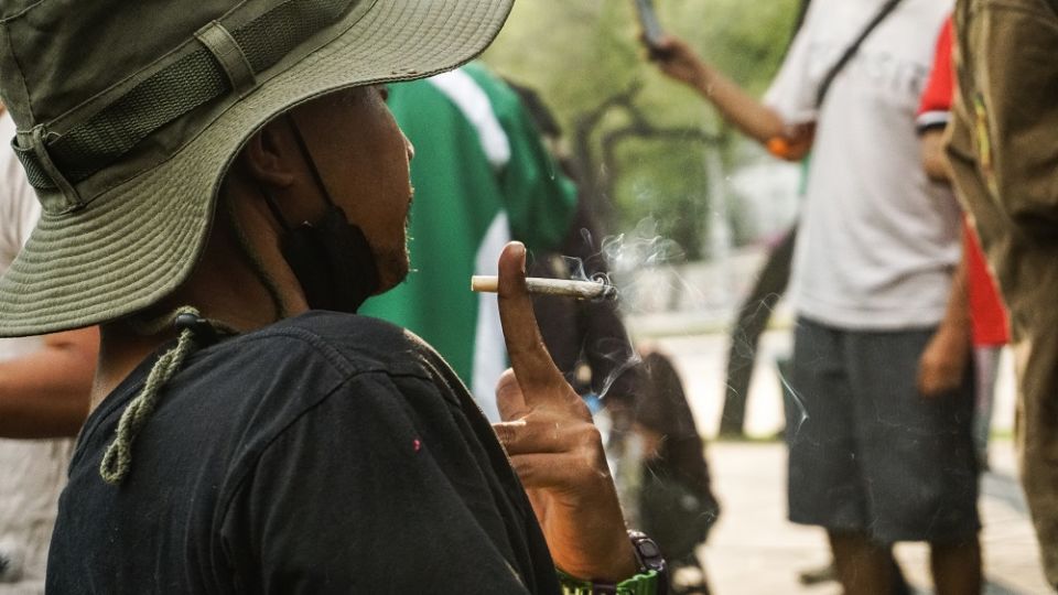 A man on Jan. 25, 2022, smokes a joint at a rally near the tourism ministry in Bangkok. Photo: Chayanit Itthipongmaetee / Coconuts