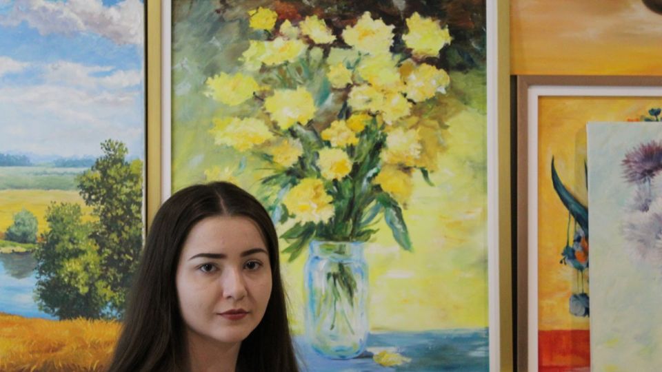 Yuliia “Juli ” Hvozdetska before her painting ‘Flowers of Victory.’ Photo: Tara Abhasakun / Coconuts