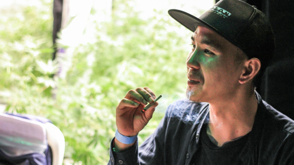 A man smokes a joint on June 12, 2022, at the Thailand 420: Legalaew event. Photo: Chayanit Itthipongmaetee / Coconuts Bangkok