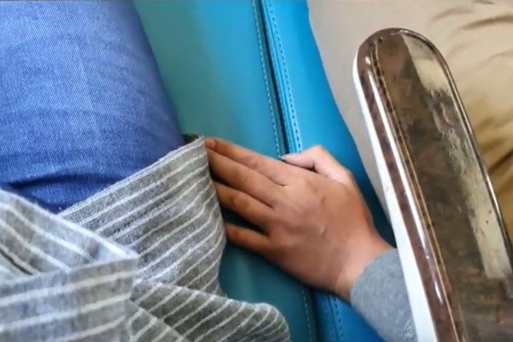 A male train passenger’s hand encroaches on the seat of a female passenger before he touches her leg. Photo: Video screengrab