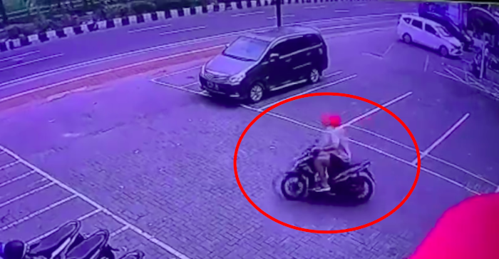 Screengrab from a video showing a foreigner snatching a helmet from an unattended motorcycle on Sunset Road. 