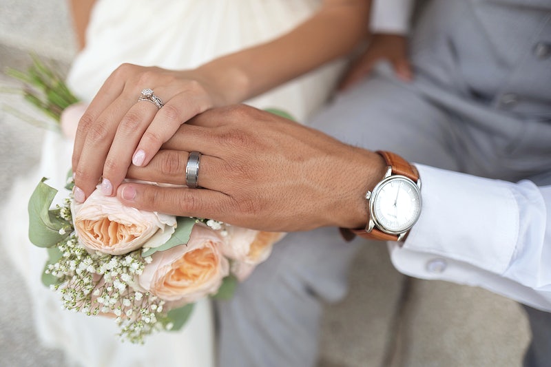 Bride and groom’s hands touching over wedding bouquet. Original public domain image from Wikimedia Commons