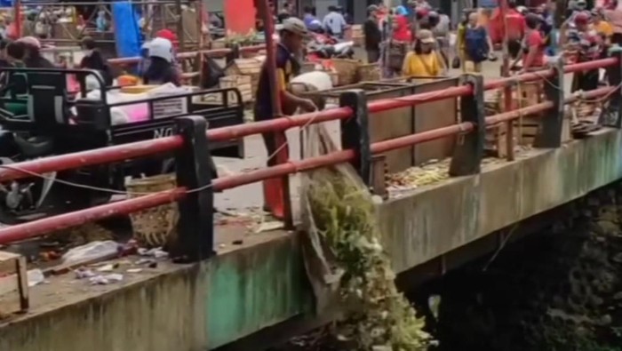 Video screengrab showing a man at Cibinong traditional market in Bogor Regency, West Java tossing a heap of waste into a river.