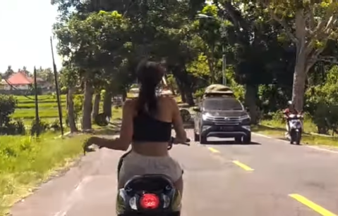 A white woman, whose identity is still unknown, was seen gyrating on her motorbike while driving without wearing a helmet on Jan. 8, 2023, on the Denpasar-Gilimanuk Road in Mendoyo. Photo: Screengrab.