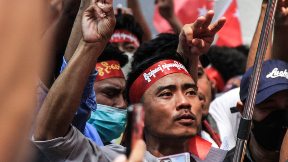 A Myanmar protester raises a three-finger salute in front of the Myanmar embassy in Bangkok on Feb. 1, 2023, to protest against military dictatorship back home. Photo: Chayanit Itthipongmaetee / Coconuts
