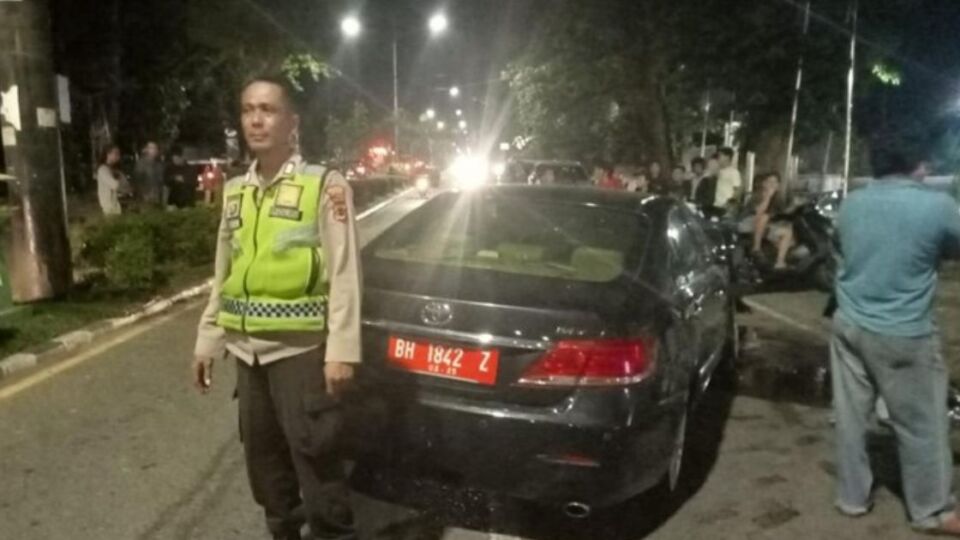 A police officer standing by a government car crashed by a high school student, whose girlfriend was naked in the passenger seat. Photo: Handout