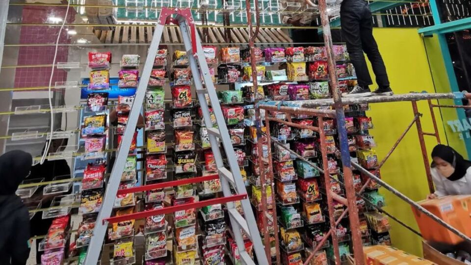 Employees stacking up a two-storey display of instant noodles at K3Mart in PIK. Photo: Instagram/@k3mart.id