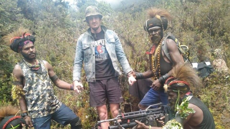 New Zealand pilot Philip Mehrtens (wearing denim jacket) standing between West Papua National Liberation Army fighters in footage released by the rebel group. Photo: Handout