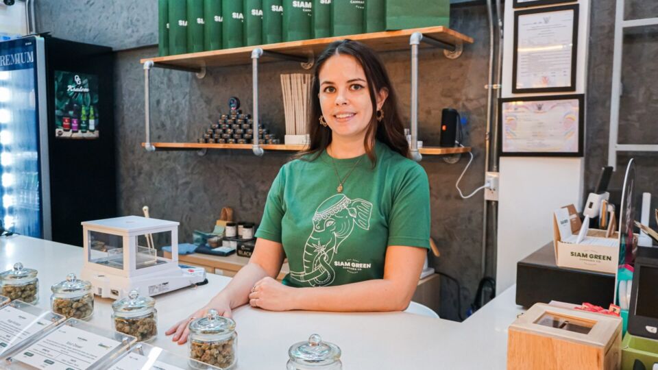 Tian Scherer stands behind the counter inside the Siam Green Cannabis store on Sukhumvit Road. Photo: Chayanit Itthipongmaetee / Coconuts