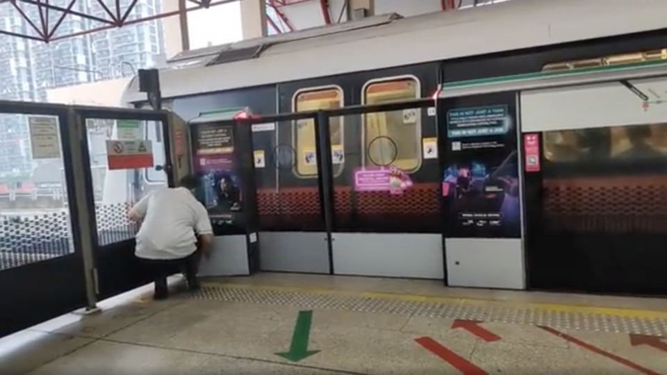 An SMRT staff trying to fix the jammed train door at Jurong East Station on Tuesday. Photo: Unfair-Bike/Reddit
