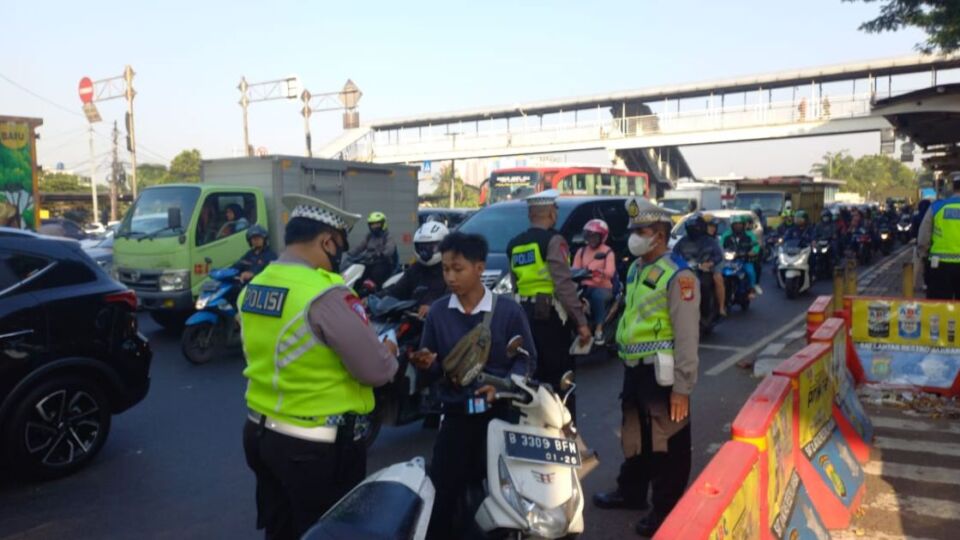 An officer handing a ticket to a motorcyclist for not wearing a helmet in West Jakarta on May 16, 2023. Photo: Twitter/@tmcpoldametro