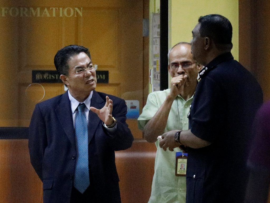 A North Korea official speaks with police at the morgue at Kuala Lumpur General Hospital where Kim Jong Nam's body is held for autopsy