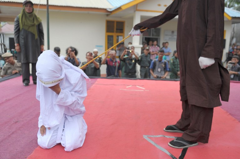 FILE PHOTO: An Acehnese woman gets caned by a religious officer, for spending time in close proximity with a man who is not her husband, which is against Sharia law, in Banda Aceh on February 27, 2017.  
Aceh is the only province in the world’s most populous Muslim-majority country that imposes sharia law. People can face floggings for a range of offences — from gambling, to drinking alcohol, to gay sex. / AFP PHOTO / CHAIDEER MAHYUDDIN