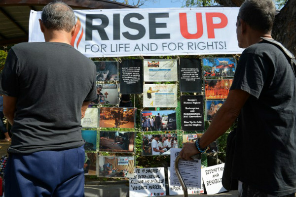 People look at a photograph exhibit of victims of extra-judicial killings in President Rodrigo Duterte’s drug war on the grounds of a church in Manila on March 1, 2017. PHOTO: AFP