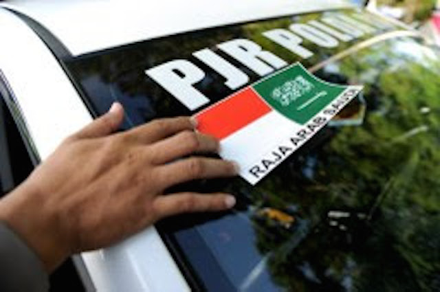 A policeman puts a sticker on a police patrol car during their preparation for Saudi Arabia’s King Salman bin Abdul Aziz ‘s visit in Nusa Dua on March 2, 2017. Photo: AFP 