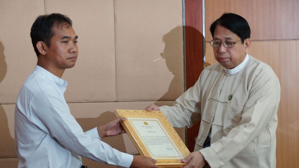 Swe Win receiving an award from Information Minister Pe Myint in 2016. Photo: MOI