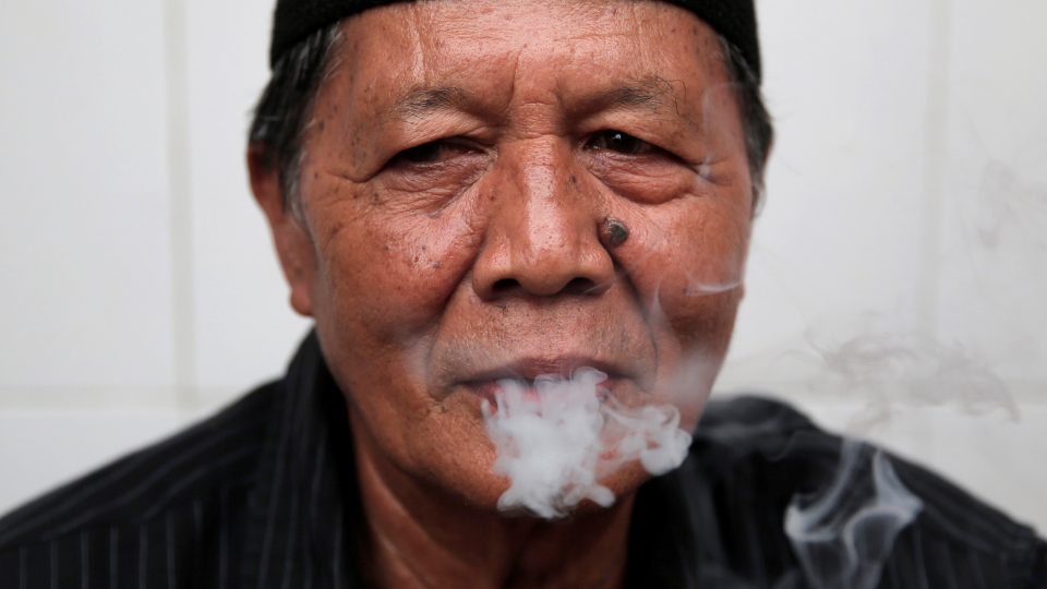 A man smokes s cigarette in Jakarta, Indonesia, March 14, 2017. Picture taken March 14, 2017. REUTERS/Beawiharta