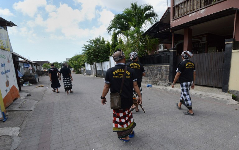 Balinese guards patrol an emtpy street in Jimbaran as the Indonesian holiday island shuts down for a day of silence to mark Nyepi, the Hindu new year, on March 31, 2014. Retailers closed their shops and many tourists stayed inside their hotels for a day of reflection that is supposed to be free from daily routine, including work and play. Guards with sticks and traditional daggers enforced the public observance among the Hindu- majority population. Photo: Sonny Tumbelaka/AFP