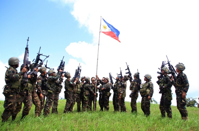 Philippine soldiers hoist a national flag after clashes with Islamic State-affiliated extremists in the mountain area of Piagapo town, Lanao del Sur province, on the southern island of Mindanao on April 25, 2017.
The Philippine military said April 25 it had killed almost 40 militants loyal to the Islamic State group, including three Indonesians and a Malaysian, in a major land and air assault in the south. / AFP PHOTO / RICHEL UMEL